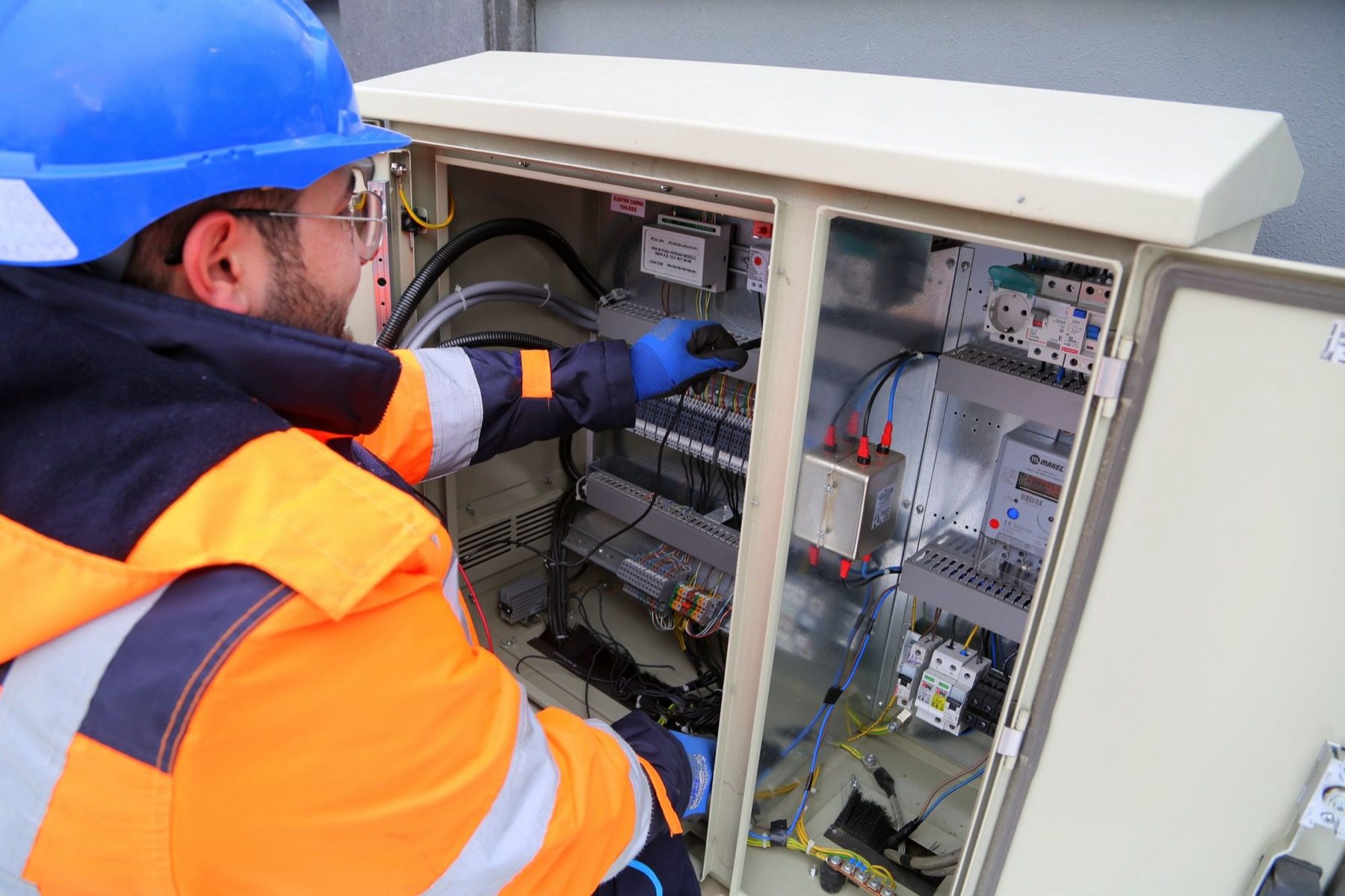An engineer working inside an electrical and mechanical control panel